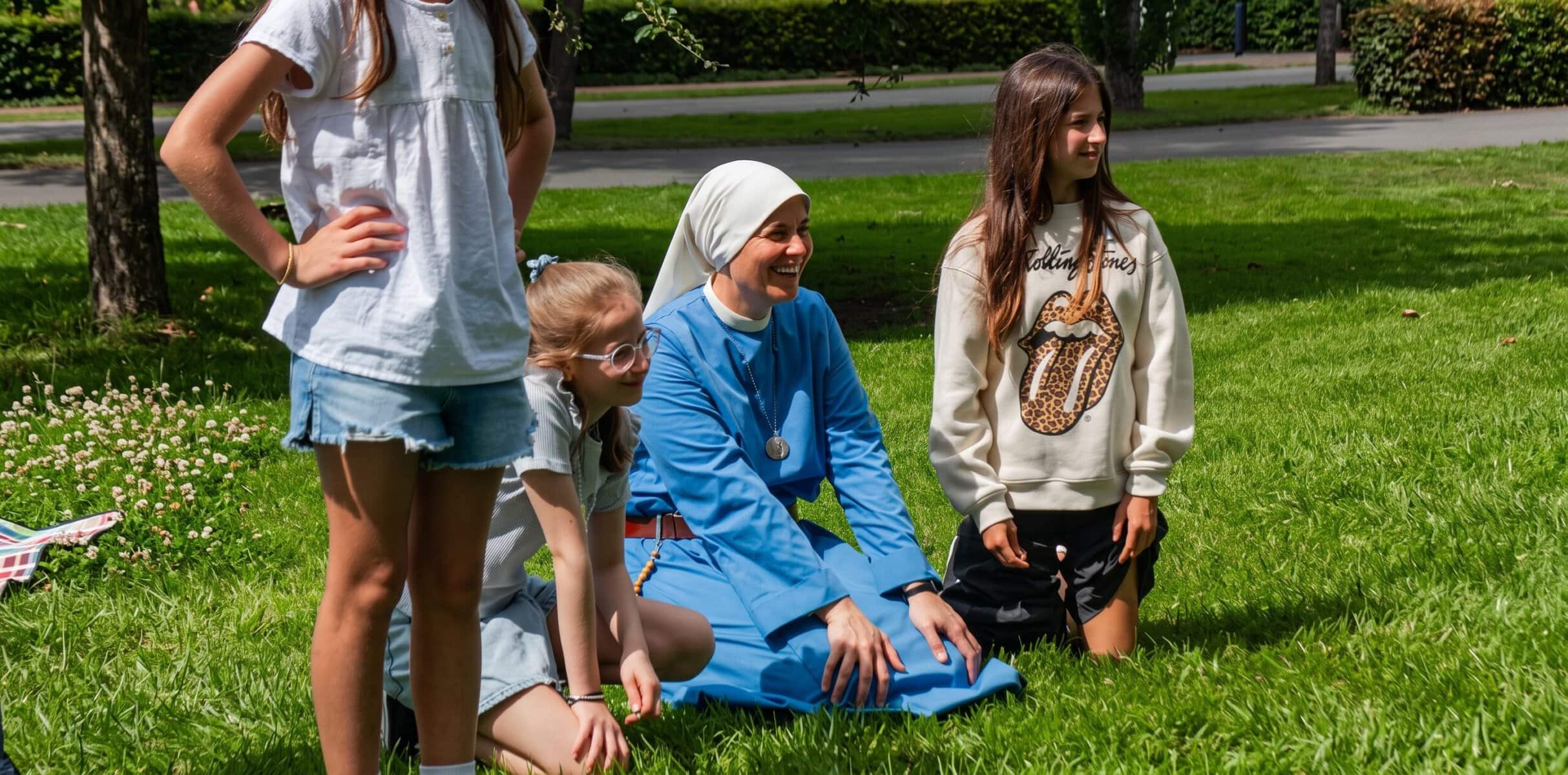 Grupo de niños y una monja en un parque, participando en actividad comunitaria.